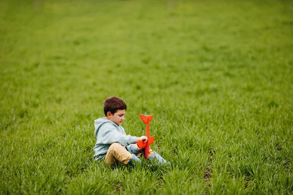 Мальчик Играет Красным Самолетом Сидит Поле Зеленой Травой — стоковое фото