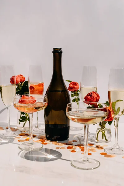 テーブルの上にピンクのバラとシャンパンとフルグラスのボトル — ストック写真