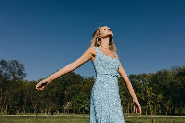 一个金发碧眼的年轻女人 穿着蓝色的衣服 享受着好天气 — 图库照片