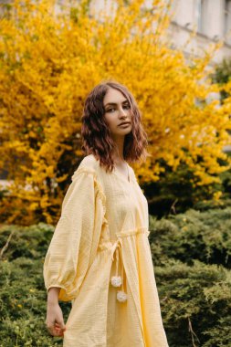 Parkta dalgalı saçlı, sarı elbiseli genç bir kadın..