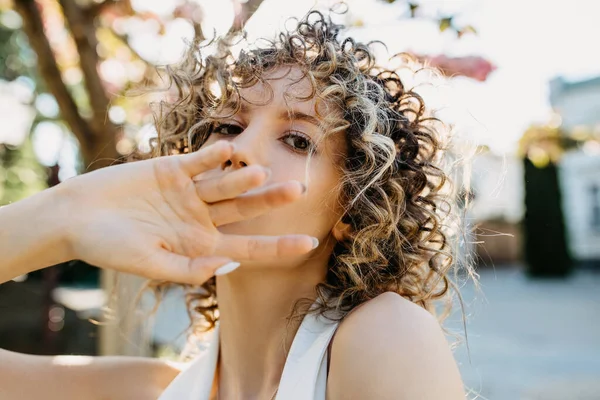 Young Woman Curly Hair Looking Camera Covering Mouth Hand — Foto de Stock