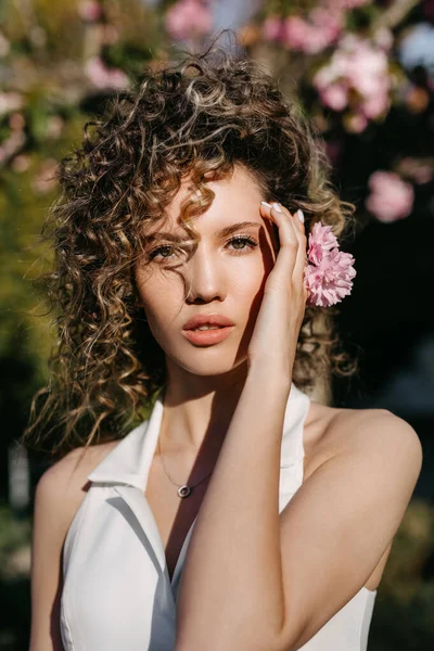 Detailní Portrét Mladé Ženy Kudrnatými Vlasy Pózující Venku Růžovými Květy — Stock fotografie