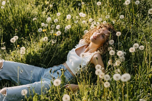 Young Woman Curly Hair Lying Field Green Grass Dandelions — Foto de Stock