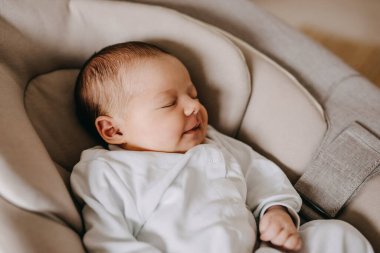 Uyurken gülümseyen ve hayal eden yeni doğmuş bir bebeğin yakın çekimi.