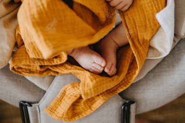 Sarı battaniyeyle örtülü yeni doğmuş bebek ayakları..