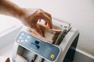 Adam 50 avroluk banknotları bir sayım makinesine koyuyor..