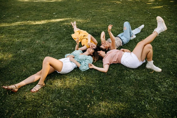 Четыре Молодые Женщины Лежащие Зеленой Траве Открытом Воздухе Парке Смеясь — стоковое фото