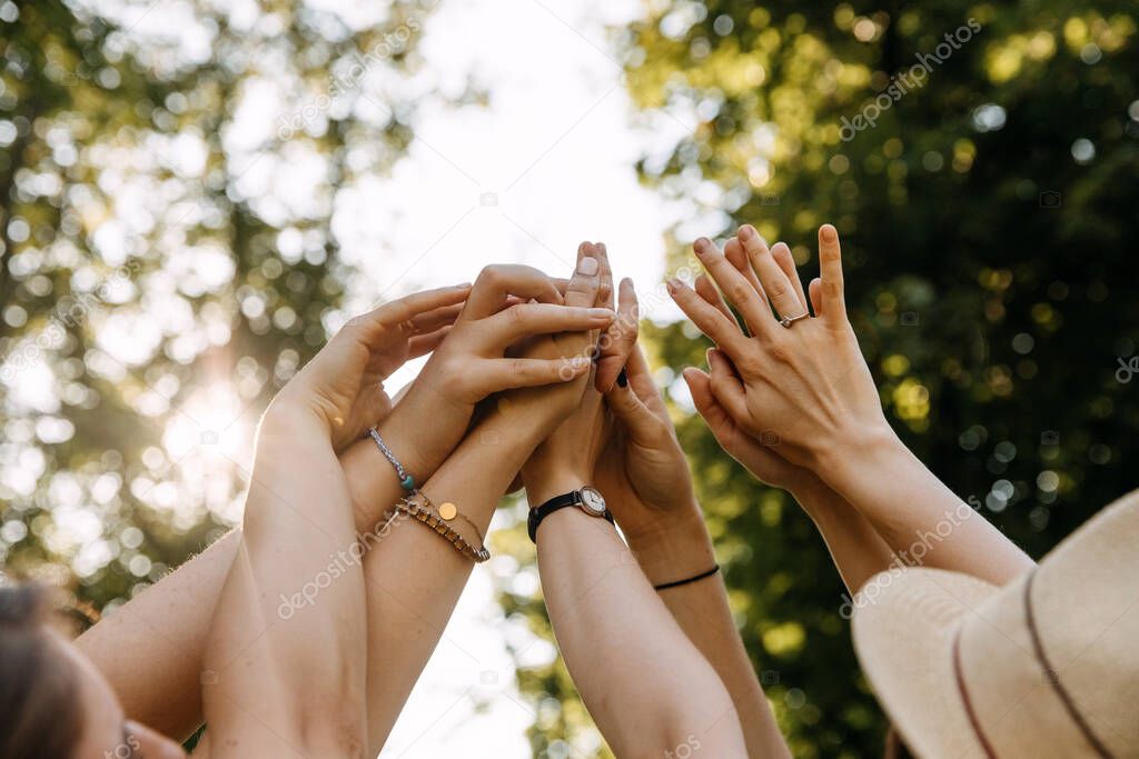 Group of women holding hands together up in the air.