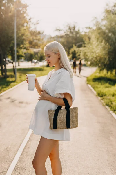 Hamile Bir Kadın Parkta Yürüyor Elinde Kahve Fincanı Tutuyor Gülümsüyor — Stok fotoğraf