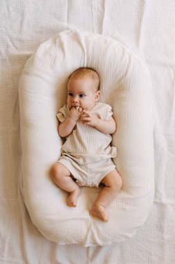 Bebek yuvasında yalın ayak uzanmış parmaklarını emiyor..