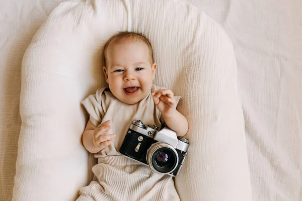 Fotograf Leżący Gnieździe Dziecka Trzymający Zabytkową Kamerę Filmową Uśmiechający Się — Zdjęcie stockowe
