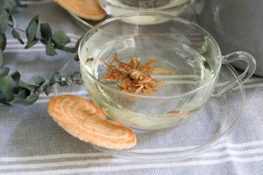 Pencere kenarında çay saati, şeffaf bardakta papatya çayı.