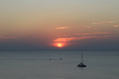 Kumsalda batan güneş, turuncu ipeksi dalganın üzerindeki güneş ışığının yansıması.