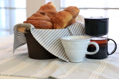 Bir sepet Fransız ekmeği, kruvasan, pencere kenarında kahvaltı.