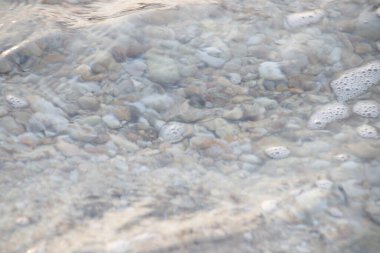 Kumsalda çakıl taşları ve deniz dalgaları, yaz tatilleri