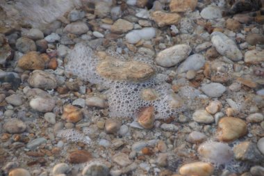 Kumsalda çakıl taşları ve deniz dalgaları, yaz tatilleri