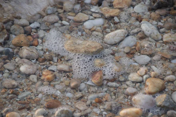 Kumsalda çakıl taşları ve deniz dalgaları, yaz tatilleri