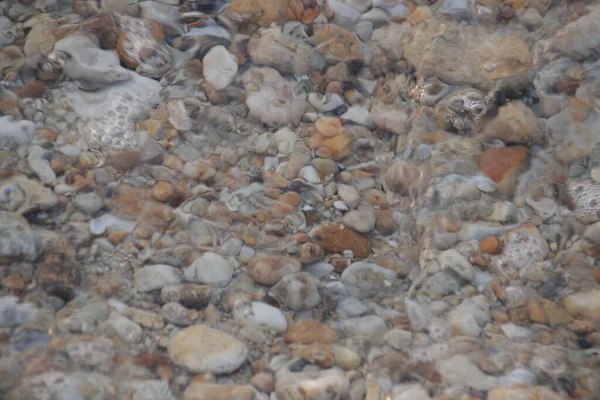 Kumsalda çakıl taşları ve deniz dalgaları, yaz tatilleri