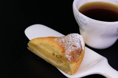 Üzerinde ezilmiş çam fıstığı ve siyah arka planda ezilmiş fındık olan Armut turtasını kapat.