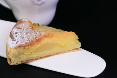 Üzerinde ezilmiş çam fıstığı ve siyah arka planda ezilmiş fındık olan Armut turtasını kapat.