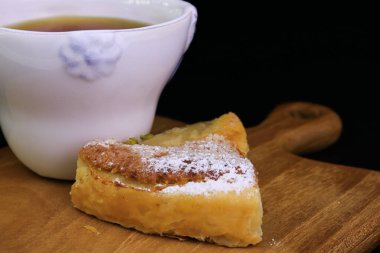 Üzerinde ezilmiş çam fıstığı ve siyah arka planda ezilmiş fındık olan Armut turtasını kapat.