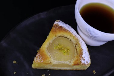 Üzerinde ezilmiş çam fıstığı ve siyah arka planda ezilmiş fındık olan Armut turtasını kapat.