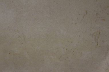 Hafif, sıcak gri bir ton ve neredeyse kumaşa benzeyen ince noktalı bir cilt ile karakterize edilmiş beton görünümlü bir yüzey.