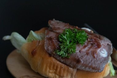 Biftek Burger 'i ahşap bir tabakta kapat, siyah arkaplan