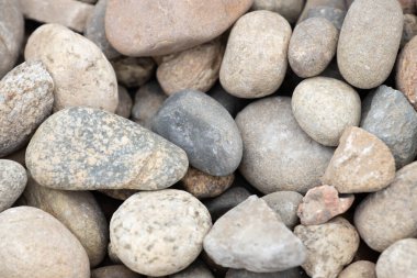Gri, bronz ve kahverengimsi tonlarda pürüzsüz nehir çakıl taşlarının doğal bir düzeni rahatlatıcı, organik bir doku yaratır..