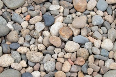 Gri, bronz ve kahverengimsi tonlarda pürüzsüz nehir çakıl taşlarının doğal bir düzeni rahatlatıcı, organik bir doku yaratır..