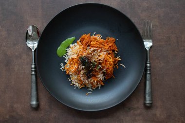 Aromatik baharatlar, otlar ve taze sebzeler veya et katmanlı uzun taneli basmati pilavı içeren lezzetli bir biryani servisi..