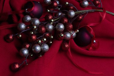 Zarif bir Noel temalı natürmort. Zengin, şenlikli kırmızılar üzerine kurulmuş. Parlayan kırmızı ve altın renkli sahte böğürtlenler narin bir kış buketi gibi sıralanır.