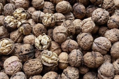 Sert, desenli kabuklarındaki cevizlerin yakın plan görüntüsü. İçindeki soluk altın çekirdekleri ortaya çıkarmak için birkaç çatlak..