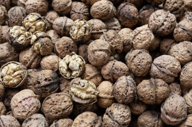 Sert, desenli kabuklarındaki cevizlerin yakın plan görüntüsü. İçindeki soluk altın çekirdekleri ortaya çıkarmak için birkaç çatlak..