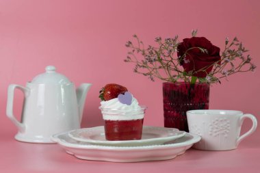 Zarif bir çilek reçeli parfe berrak bir fincanda sunulur, canlı kırmızı meyve jölesiyle kaplanır ve üzerinde bol miktarda krem şantili krema bulunur..