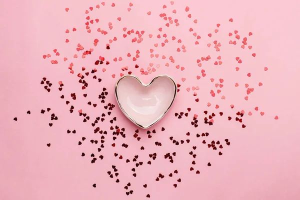 Miska w kształcie serca z rozproszonym czerwonym konfetti — Zdjęcie stockowe
