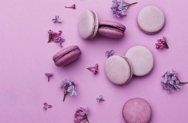 Menekşe ve leylak desenli badem kurabiyeleriyle mor arka planda leylak çiçekleri.