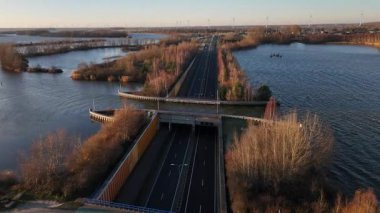 Altın ışık suyun üzerinde dans ederken Aquaduct Veluwemeer 'deki çarpıcı anı tecrübe edin. Doğa ve mimari, izleyicileri büyüleyen büyüleyici bir manzara içinde birleşir..
