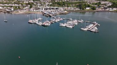 Parlak renkli tekneler Kinsale Limanı 'nın sakin sularında hafifçe sallanır. Resimli dekor, bereketli yeşillik ve canlı marina aktiviteleriyle sahil cazibesini sergiliyor. Hepsi ılık ışıkla yıkanmış..