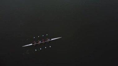 Adanmış bir takım zarif bir şekilde Gent 'in sakin sularında kürek çekerek takım çalışmasını ve yeteneklerini sergiliyor. Huzurlu çevre, nehirdeki bu sabahın erken saatlerindeki etkinliğin güzelliğini arttırır..