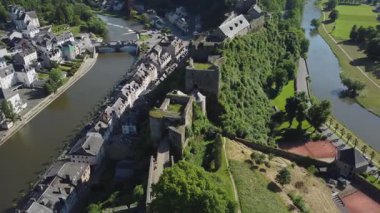Bu video, sarmal bir nehir boyunca uzanan ve görkemli bir şatoya bakan büyüleyici bir Bouillon kasabası görüntüsü sunuyor.