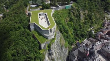 Belçika 'nın Dinant kasabasına bakan tarihi bir kale olan Dinant Kalesi' nin çarpıcı bir hava manzarası. Kale yemyeşil yeşilliklerle çevrilidir ve ziyaretçiler surlar boyunca yürürken görülebilir..