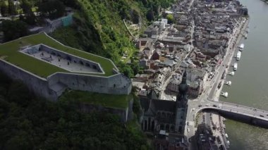 Dinant, Belçika 'nın panoramik bir manzarası, Meuse Nehri' ne bakan sarmal bir uçuruma tünemiş heybetli kaleyi gösteriyor. Tekneler su üzerinde ilerlerken, tarihi kasaba aşağılara doğru yayılıyor, zengin tarihin bir kanıtı olarak..