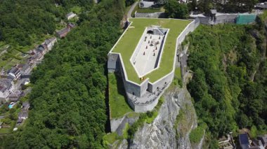 Dinant Kalesi 'nin havadan görünüşü. Pahalı kasabaya bakan dik bir uçurumun tepesine tünemişti. Yeşil çatısı ve dolambaçlı yolları olan kale, şehrin zengin tarihinin bir kanıtı olarak duruyor..