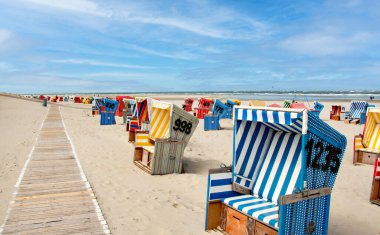 Beach baskets on a sandy beach with blue sky, on the island of Langeoog clipart