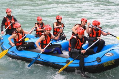 Group of happy people with guide whitewater rafting and rowing. clipart