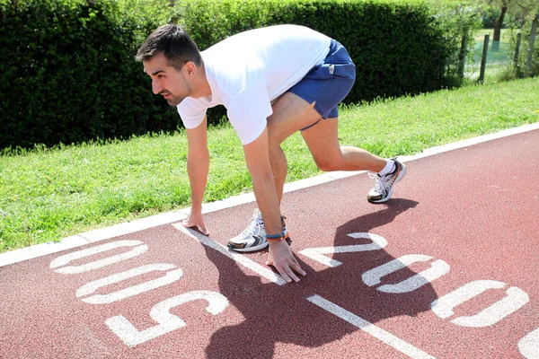 Hombre atlético en pista comenzando a correr — Foto de Stock