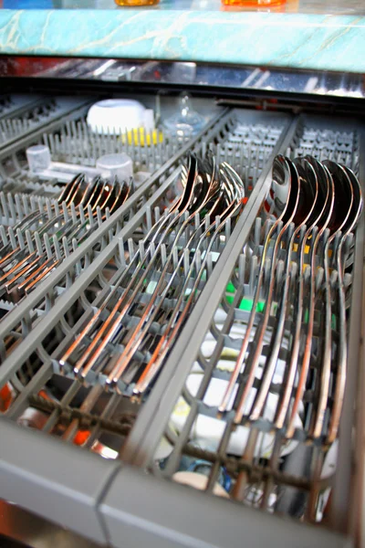 Open dishwasher with clean spoons, selective focus