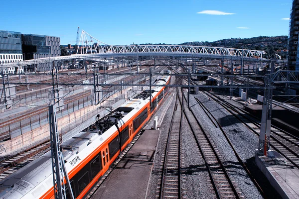 Trein vertrekt de treinstation in Oslo met moderne gebouwen. — Stockfoto