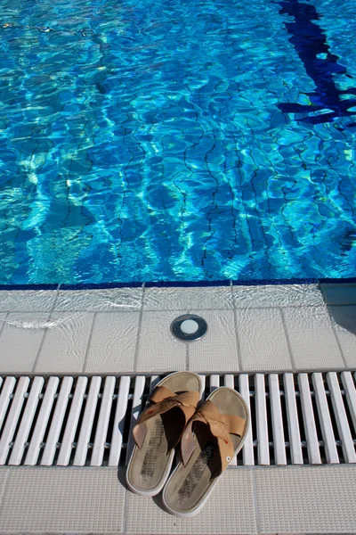 Infradito accanto alla piscina blu — Foto Stock